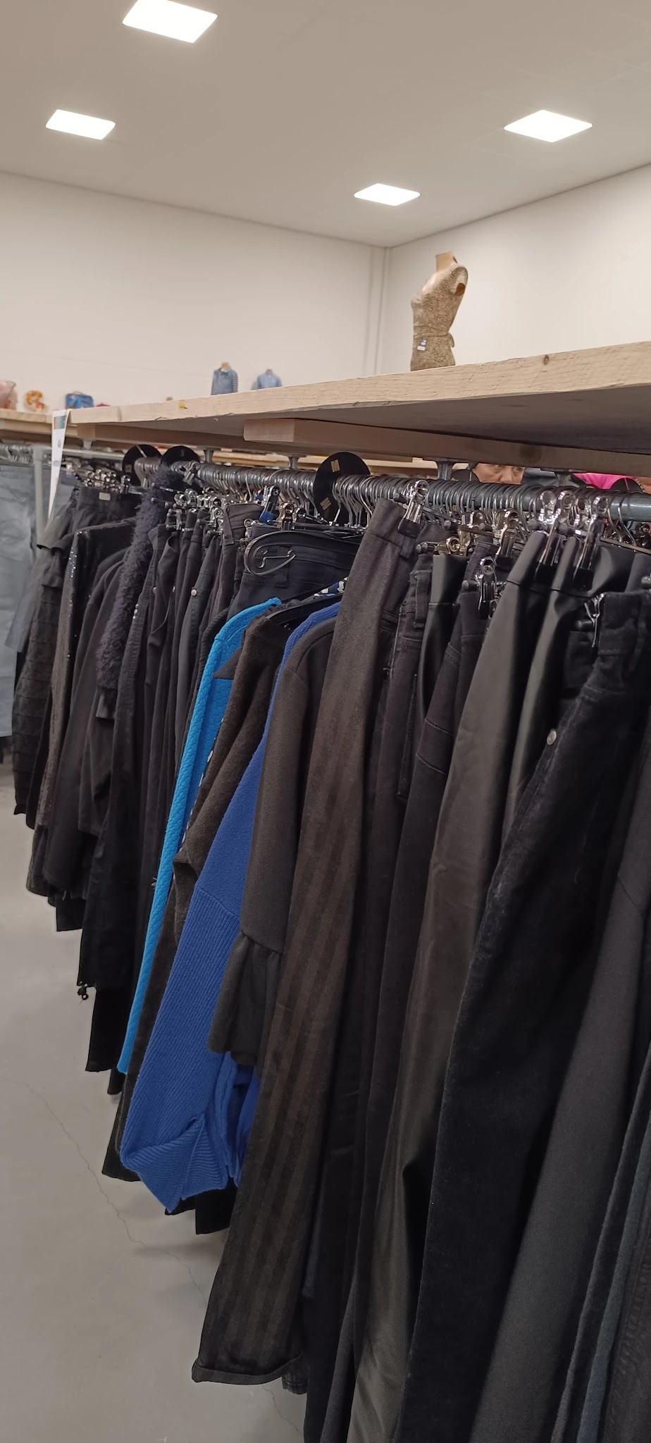 Rekken met tweedehands broeken en jeans in verschillende kleuren, waaronder zwart, bruin en blauw