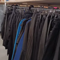 Rekken met tweedehands broeken en jeans in verschillende kleuren, waaronder zwart, bruin en blauw
