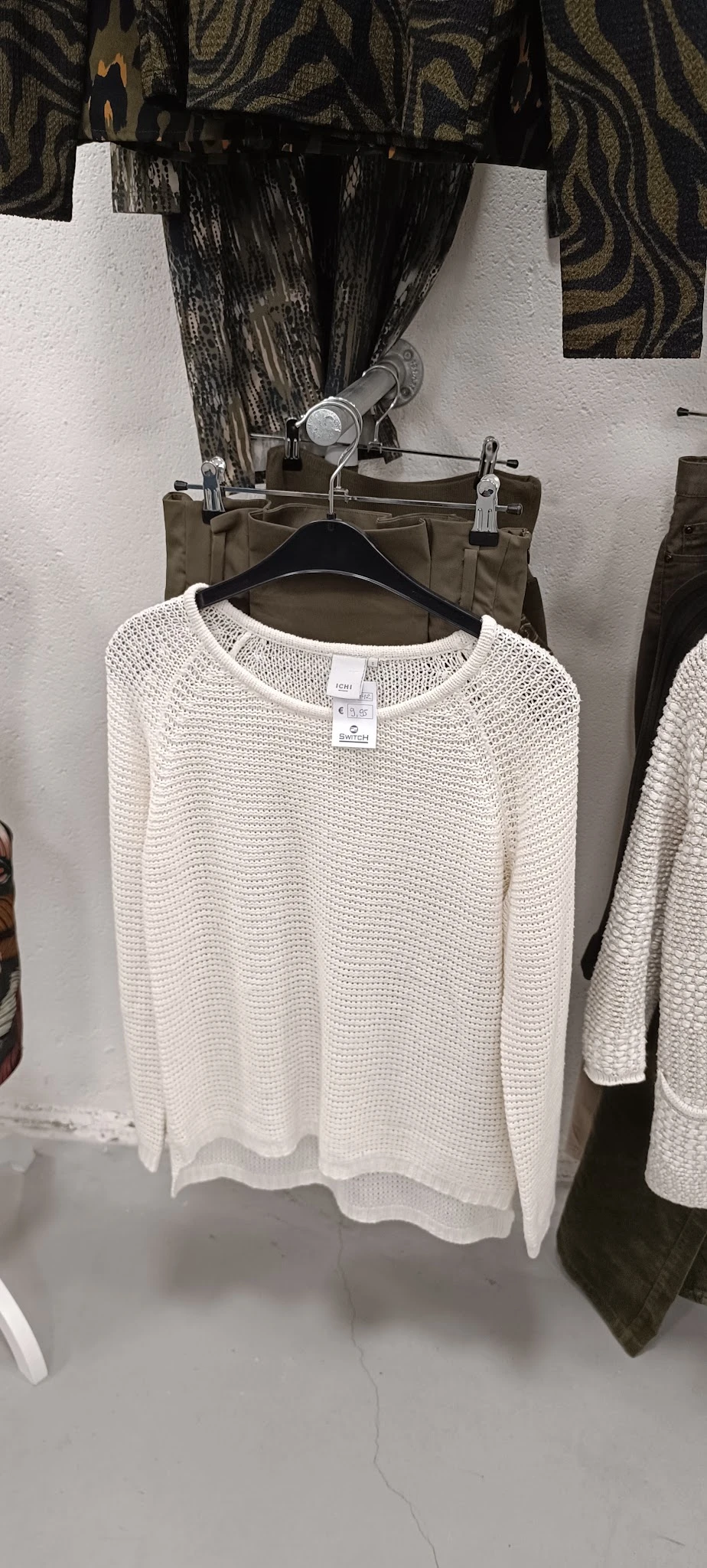 Beige gebreide trui op hangers in tweedehands winkel