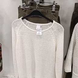 Beige gebreide trui op hangers in tweedehands winkel