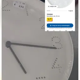 Wandklok met zwarte wijzers en getallen op witte wijzerplaat