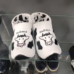 Paar witte baby slofjes met koe-print en 'Holland' tekst
