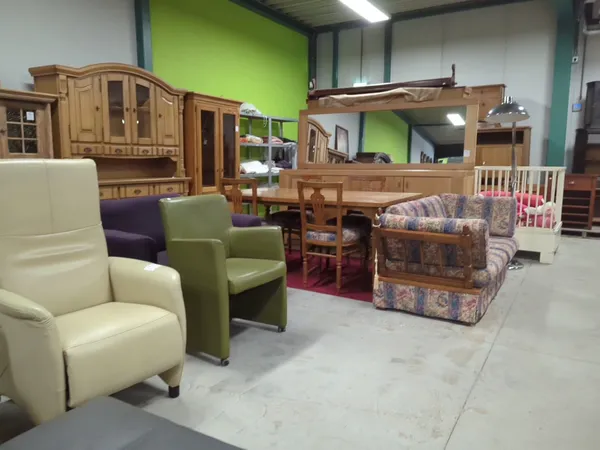 Kringloopwinkelruimte met diverse meubels: stoelen, kasten, beds en een antieke koffer op rood tapijt