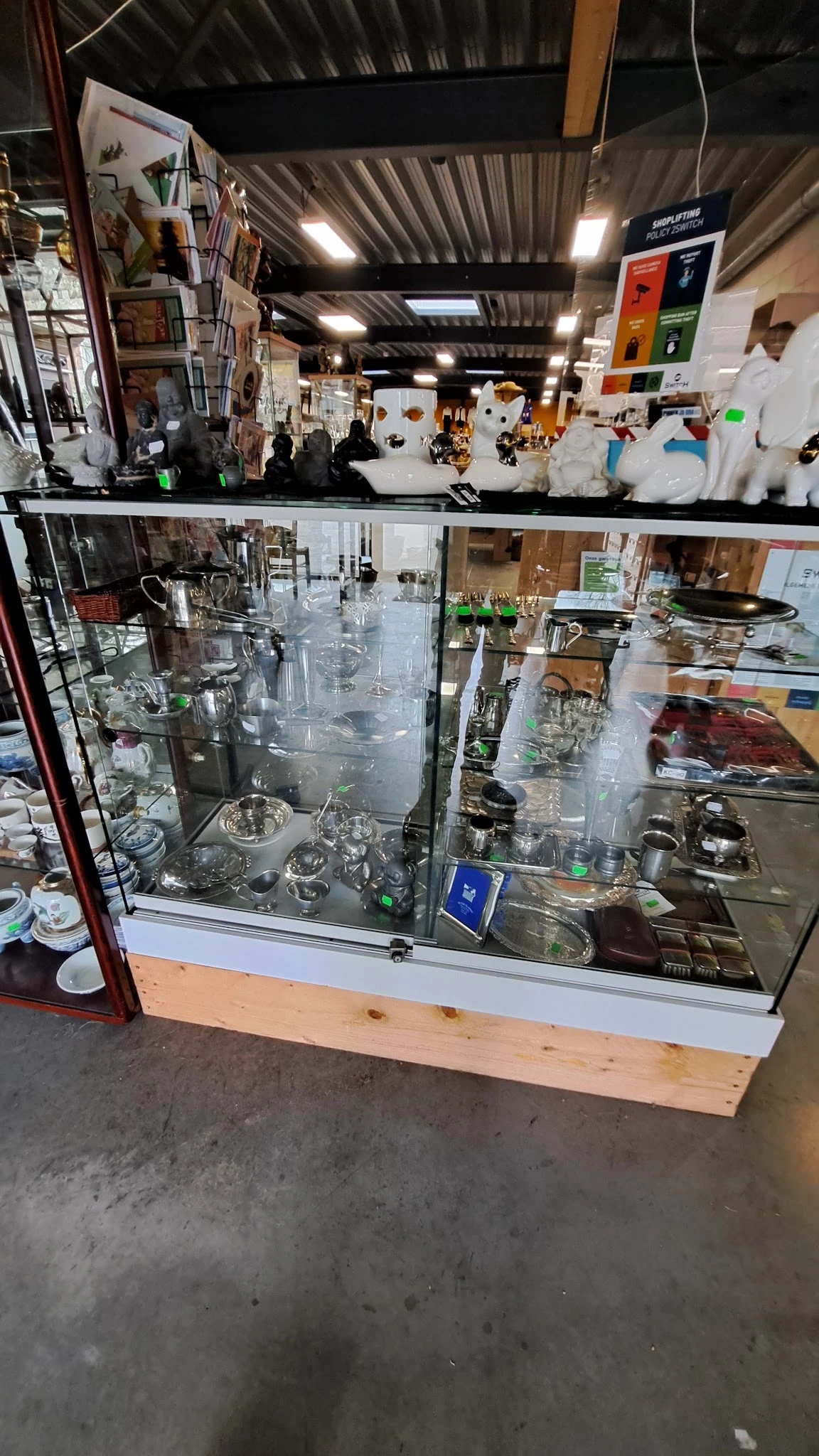 Glazen vitrinekasten met glaswerk, servies en keramische artikelen in de kringloopwinkel