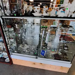 Glazen vitrinekasten met glaswerk, servies en keramische artikelen in de kringloopwinkel