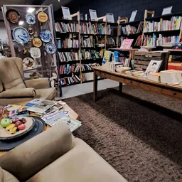 Gezellige leeshoek met fauteuil, lage tafel met fruitmand en tijdschriften, boekenrekken op de achtergrond