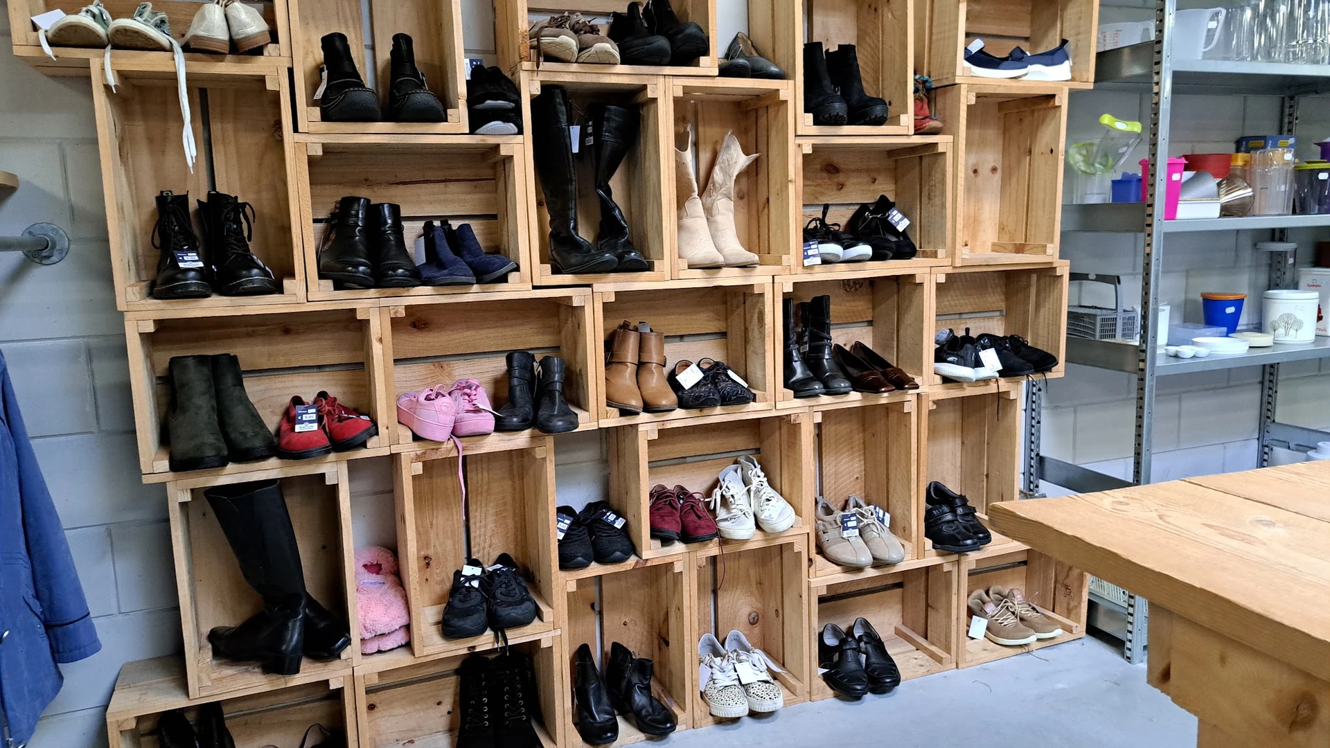 Houten stellingkast met diverse tweedehands schoenen en laarzen uitgestald