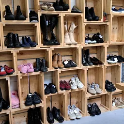 Houten stellingkast met diverse tweedehands schoenen en laarzen uitgestald