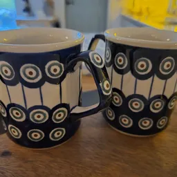 Twee zwarte bekers met wit cirkelpatroon op houten tafel