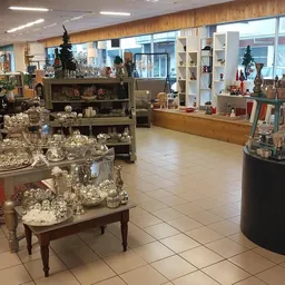 Winkelinterieur met diverse kerstdecoraties uitgestald op tafels en in vitrines, houten wand en grote ramen