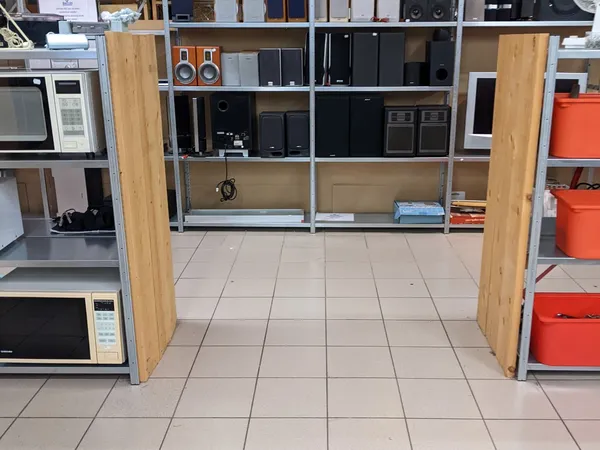 Winkelvloer met stellingen vol elektronicaartikelen, zwarte speakers en apparatuur in kringloopwinkel