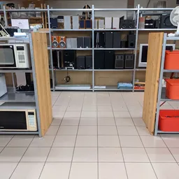 Winkelinterieur met stellingen vol elektronica, huishoudapparatuur en rode containers