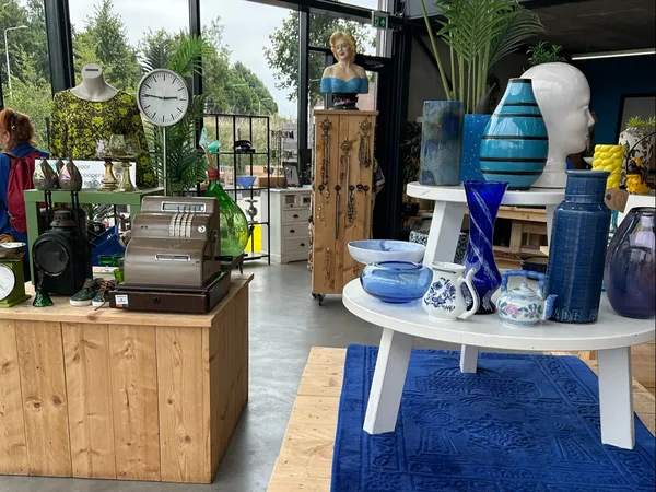Winkelinterieur met uitgestalde huishoudelijke artikelen, decoratie en een blauwe vloerkleed