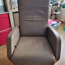 Grijze leren fauteuil met armleuningen, vooraanzicht in een woonkamer