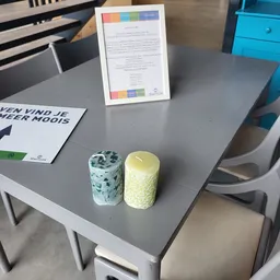 Twee decoratieve kaarsen op een grijze tafel naast informatiebladen