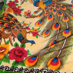 Close-up van een decoratieve doek of wandtapijt met peacock-motief, kleurrijke veren en bloemenpatronen in rood, geel, oranje