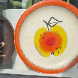 Decoratief bord met oranje rand en appelmotief in geel en rood