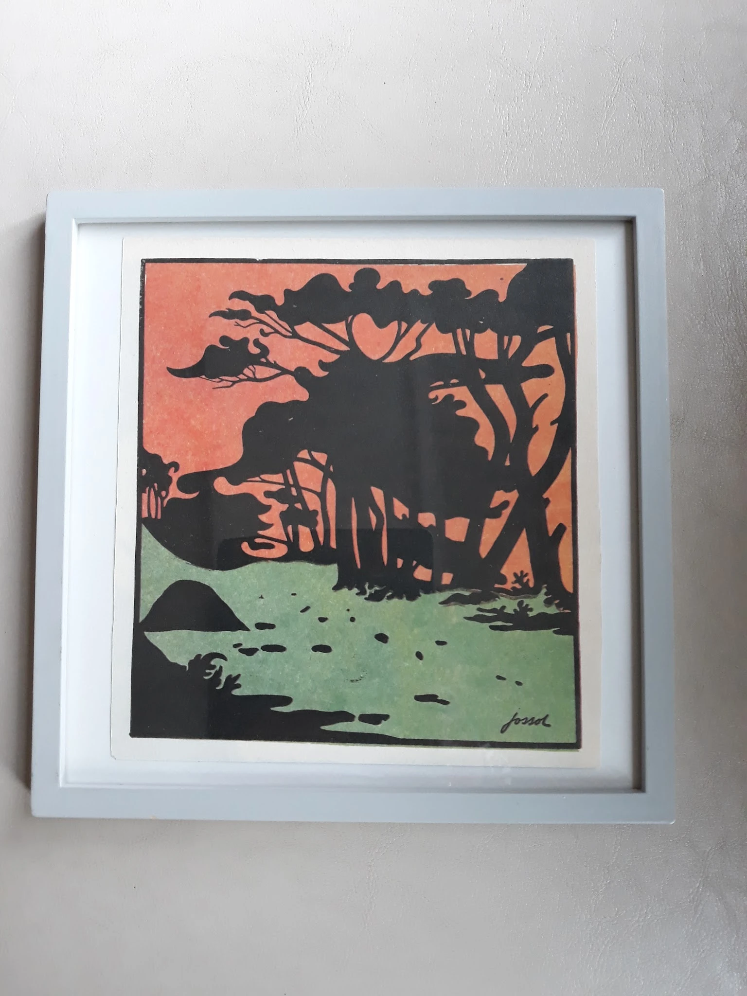 Ingelijste kunstprint met silhouetten van bomen en een gebouw tegen een oranje en groene achtergrond