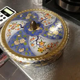 Decoratieve porseleinen doos met blauw glazuur en bloemmotieven, goudkleurige rand en bronzen knop