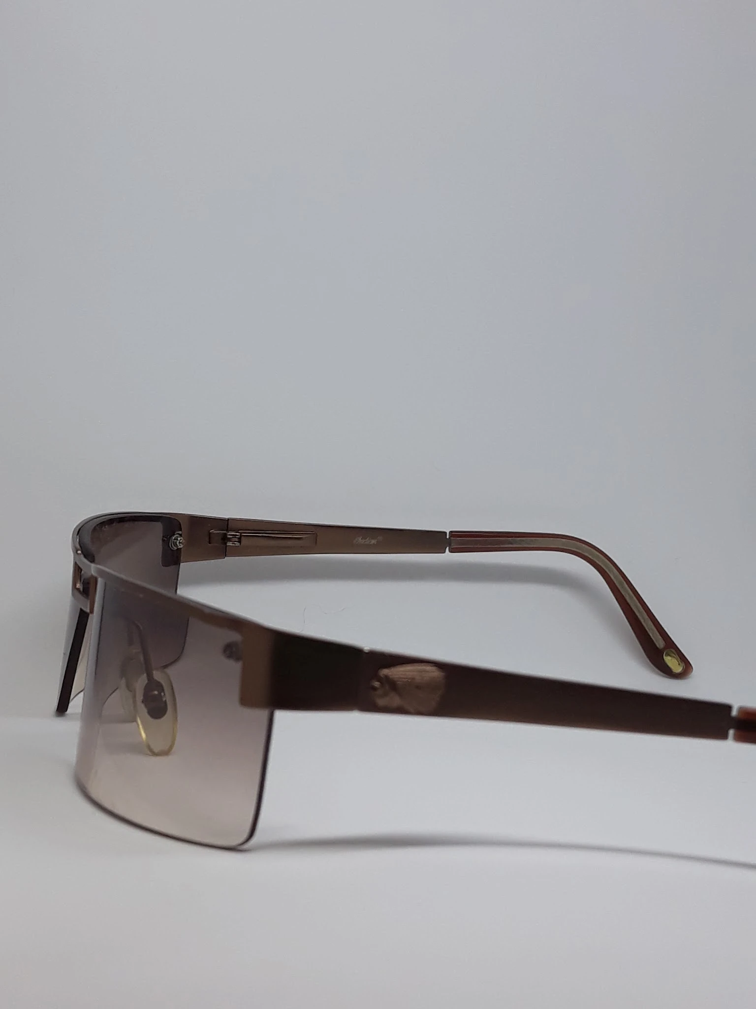 Close-up van een bruine zonnebril met donkere glazen en metalen details.