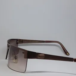 Close-up van een bruine zonnebril met donkere glazen en metalen details.
