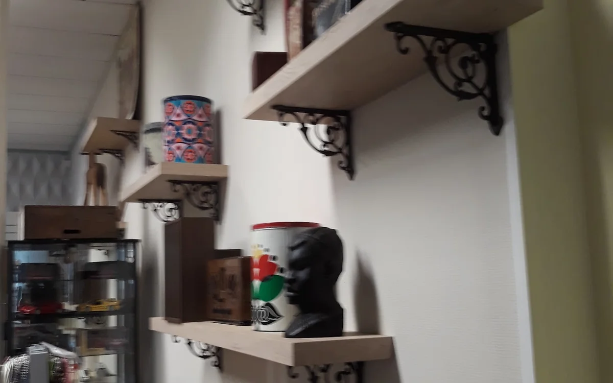 Witte muurplanken met decoratieve steundragers, voorzien van vintage items en kunstobjecten