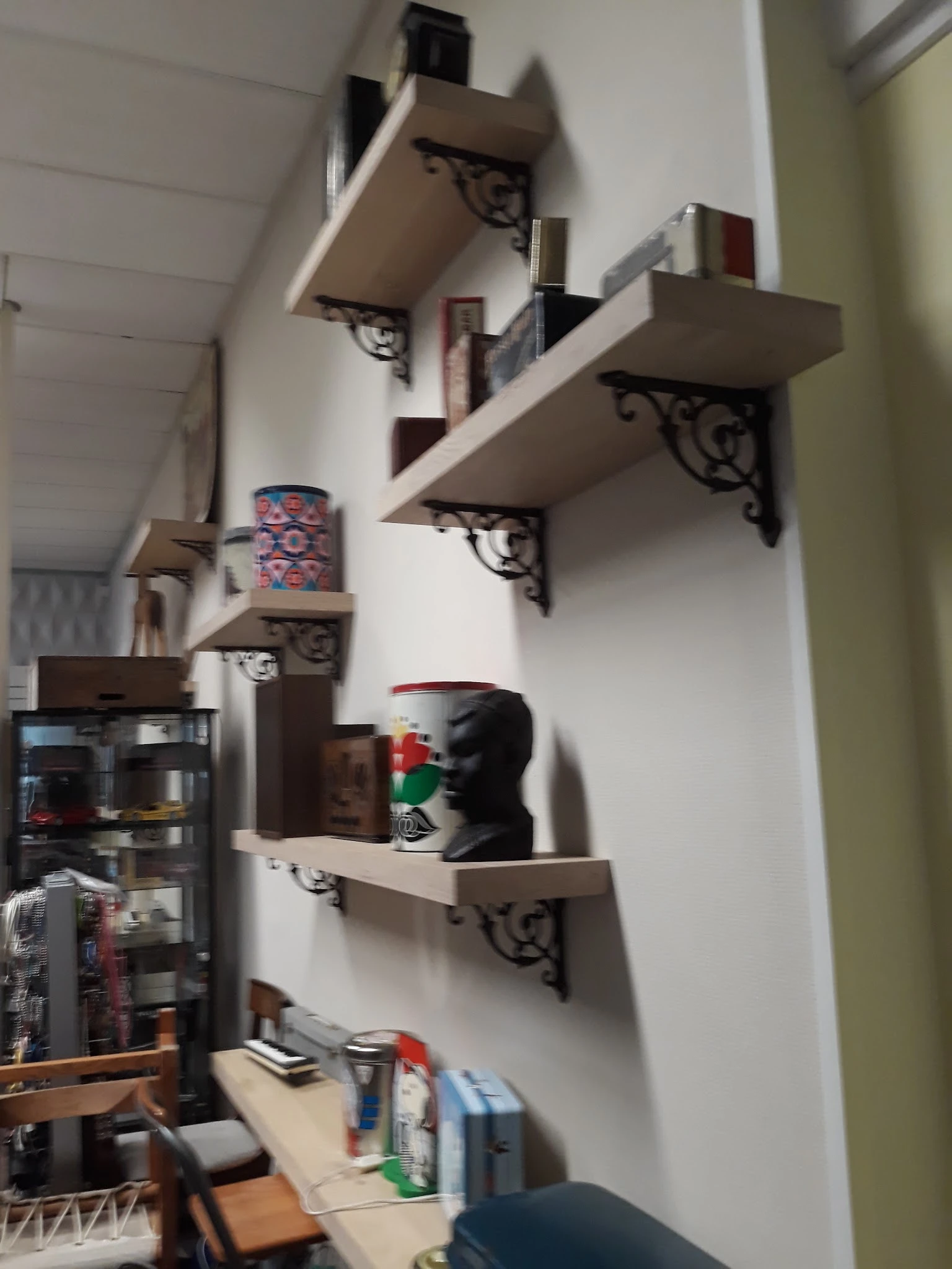Witte muurplanken met decoratieve steundragers, voorzien van vintage items en kunstobjecten