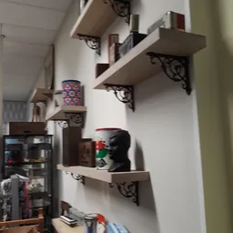 Witte muurplanken met decoratieve steundragers, voorzien van vintage items en kunstobjecten