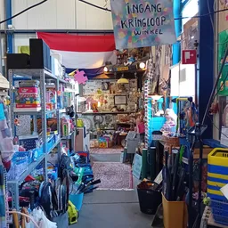 Winkelinterieur met fietsen, speelgoed en diverse spullen langs de wanden en Nederlands vlaggen aan het plafond