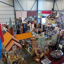 Overzicht van kringloopwinkel met diverse spullen, kleding, meubels en decoratie uitgestald op vloer en stellingen, Nederland