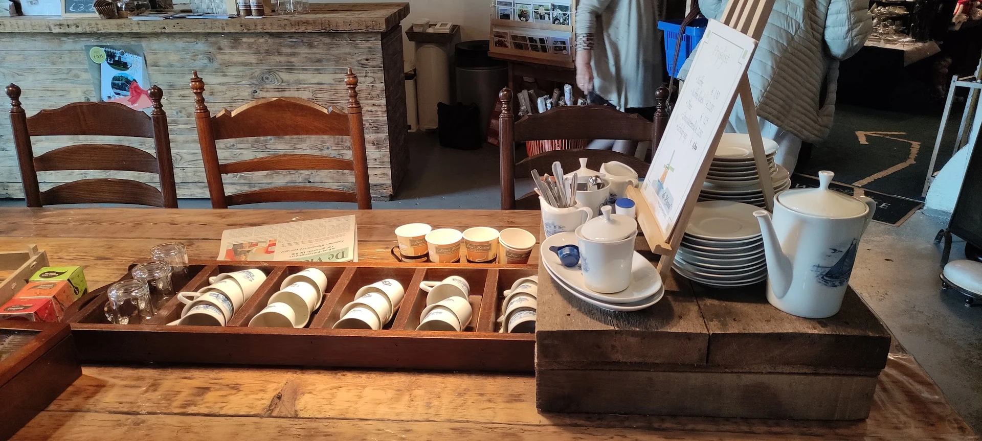 Uitgestalde serviesgoed in houten displays op een houten tafel in de winkel