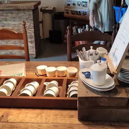 Uitgestalde serviesgoed in houten displays op een houten tafel in de winkel