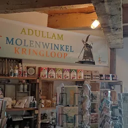 Winkelinterieur met stellingen vol spullen, winkelnaambord met molen aan plafond