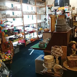 Binnenaanzicht van kringloopwinkel met diverse spullen, meubels en artikelen verspreid over de vloer en in stellingen