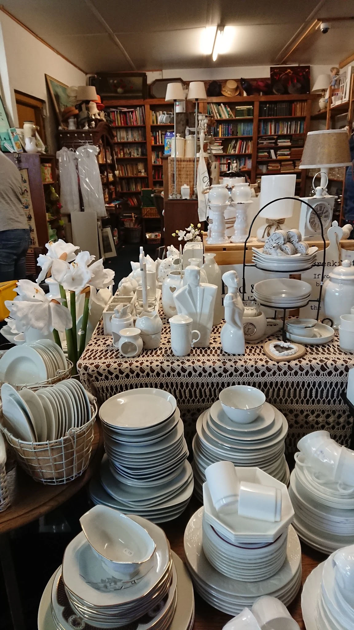 Uitstalling van wit servies, kandelaars en decoratieve items op tafel met patroonkleed