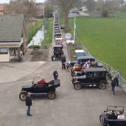 Vintage automobiles verzameld op een erf met toeschouwers