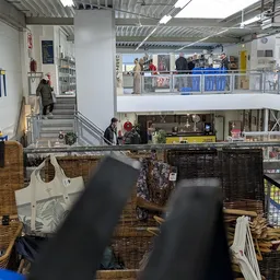 Winkelinterieur met mezzanine, stellingen met spullen en bezoekers op de begane grond