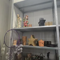 Stellingkast met decoratieve items: gouden beeldjes, gouden ster, kaarsen, sieraden en een paarse dromenvanger
