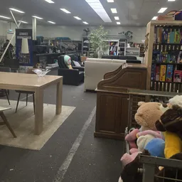 Winkelvloer met houten tafel, meubels, boekenrek en speelgoed in een kringloopwinkel