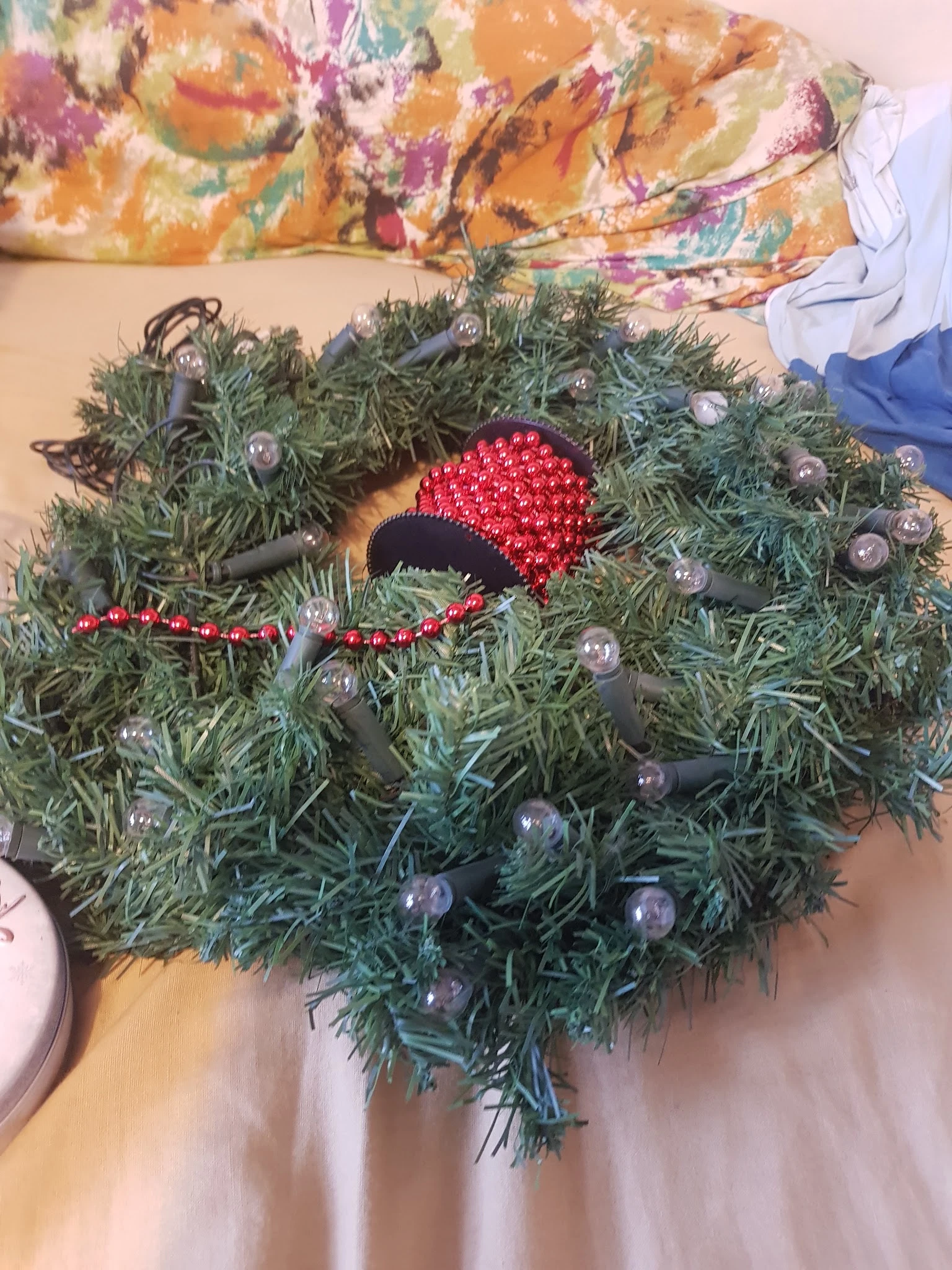 Kerstdecoratie: groene krans versierd met rode kralen en zilveren kerstballen