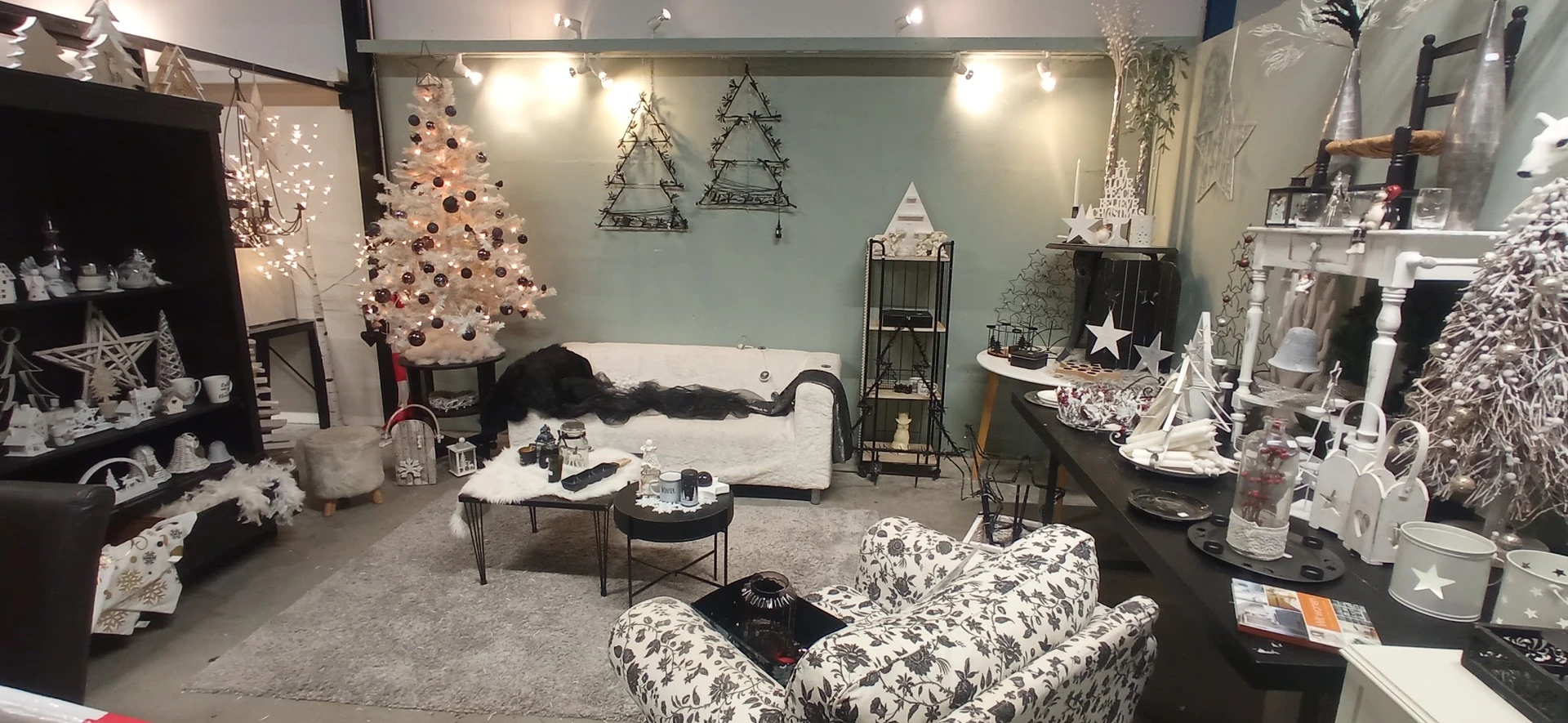 Winkelbinnenkant versierd met kerstdecoratie: witte kerstboom, zitmeubels, kroonluchters en huisraad