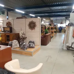 Winkelvloer van kringloopwinkel met meubels, kleding aan rekken, en diversen huishoudelijke spullen