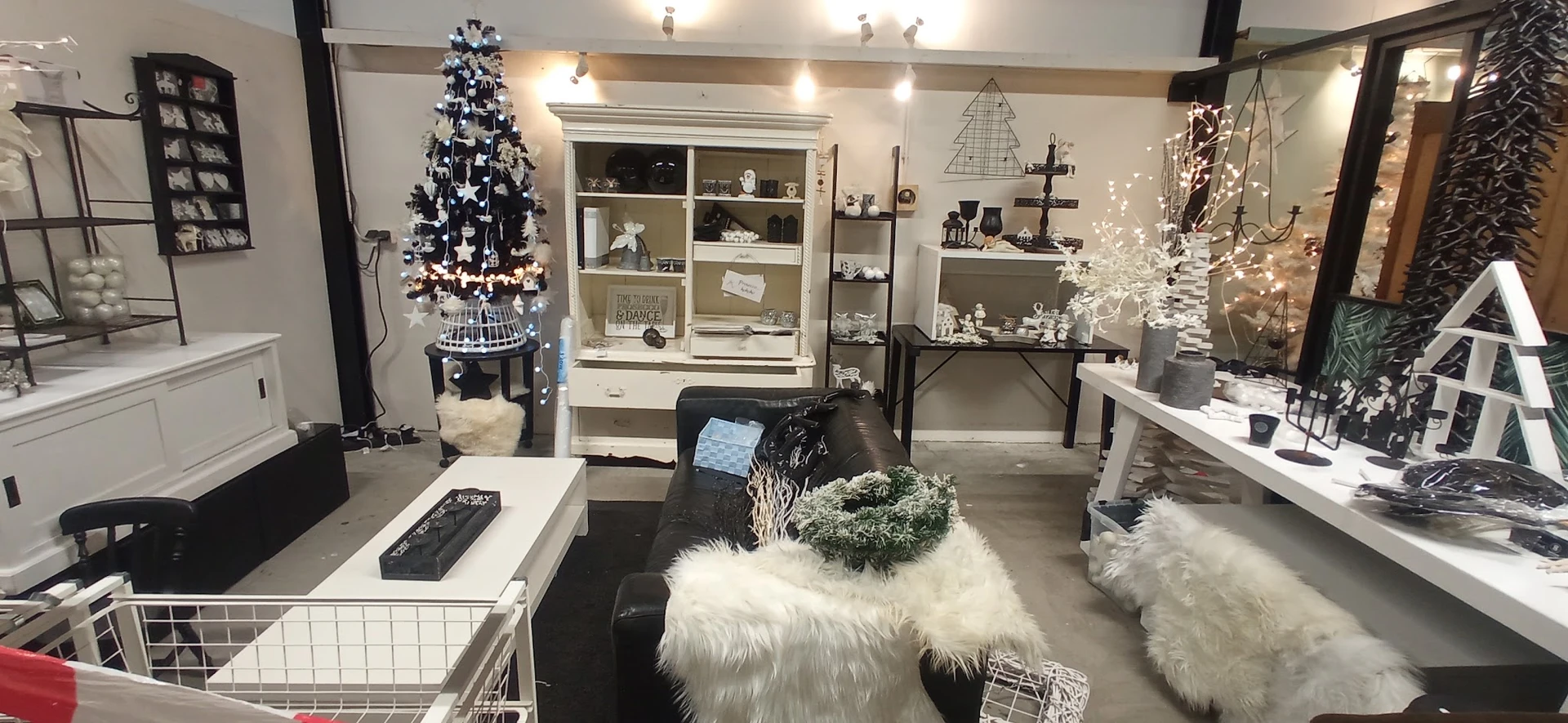 Winkelinterieur met kerstdecoratie, witte bomen, verlichte displays en witte bontmeubilair