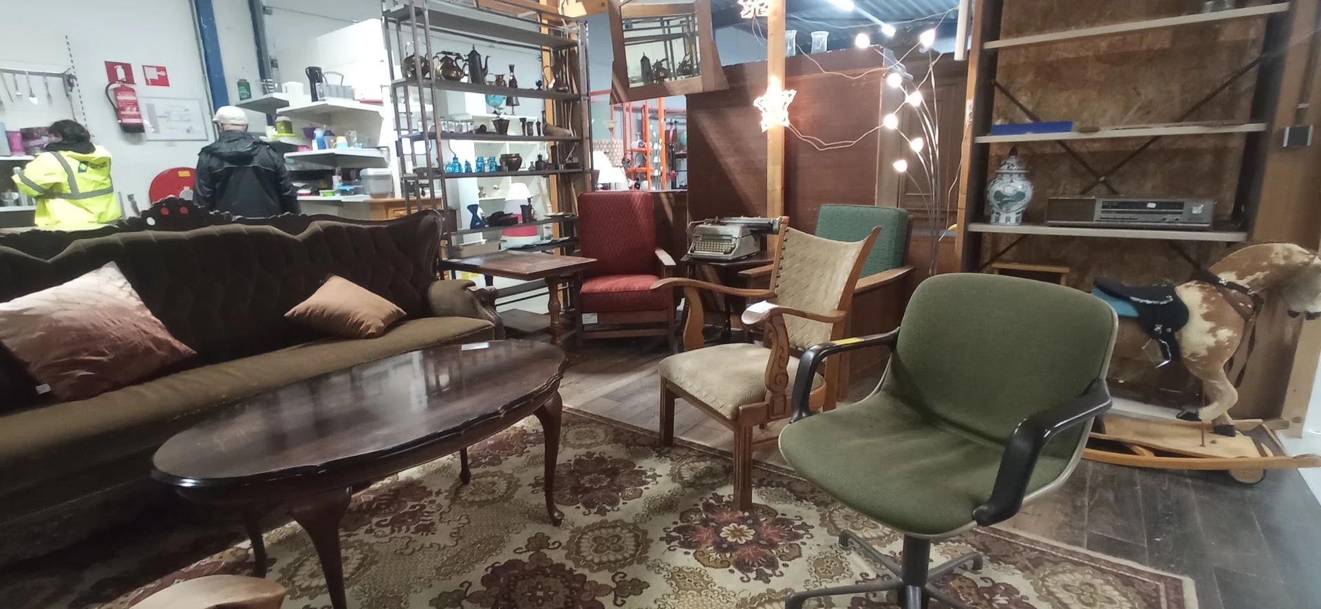 Ingerichte zithoek met vintage meubels, fauteuils en een salontafel op een oosters tapijt