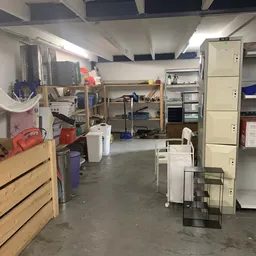 Winkelvloer met stellingen, dozen en diverse spullen; rommelig werkgebied