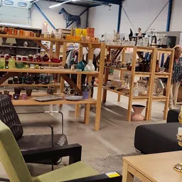Binnenzicht van kringloopwinkel met houten stellingen, meubels en uitgestalde spullen op meerdere niveaus