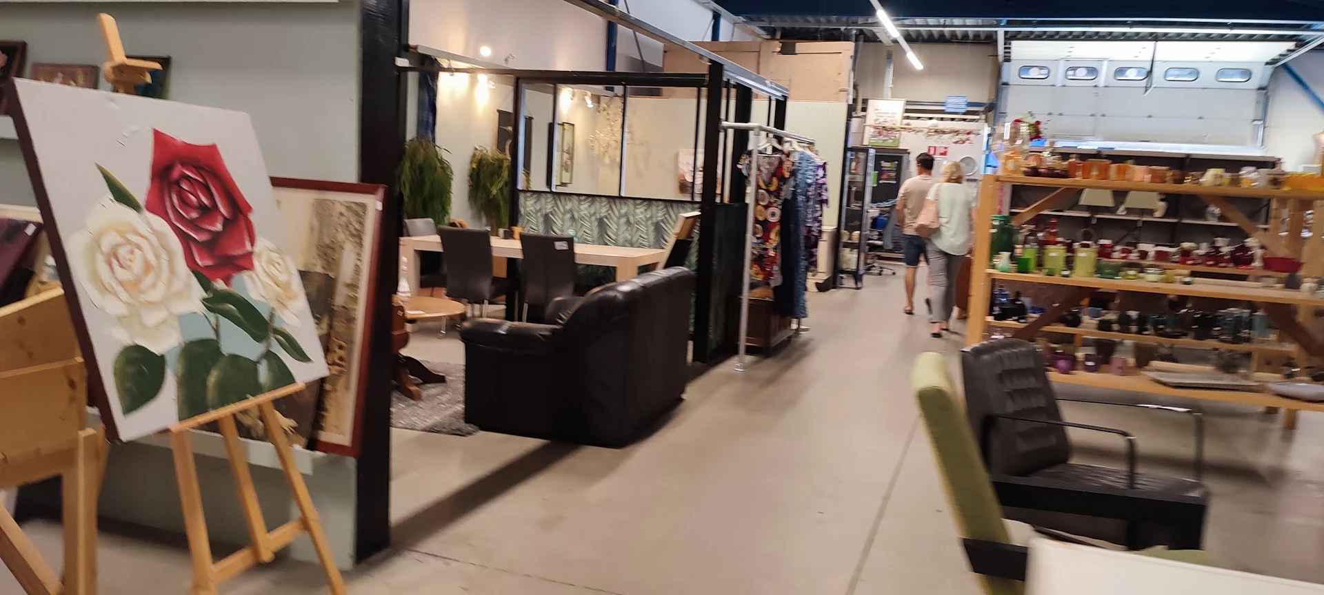 Winkelinterieur met zithoek, stellingen met kleding en diverse meubels en spullen