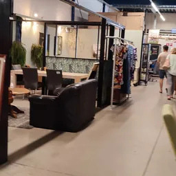 Winkelinterieur met zithoek, stellingen met kleding en diverse meubels en spullen