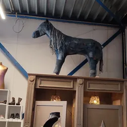 Decoratief paardenstandbeeld van donker materiaal met franjes, opgesteld op houten kastjes met verlichting
