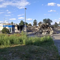 Bedrijfsterrein met kantoorgebouw en bergen gerecycled materiaal achter hek